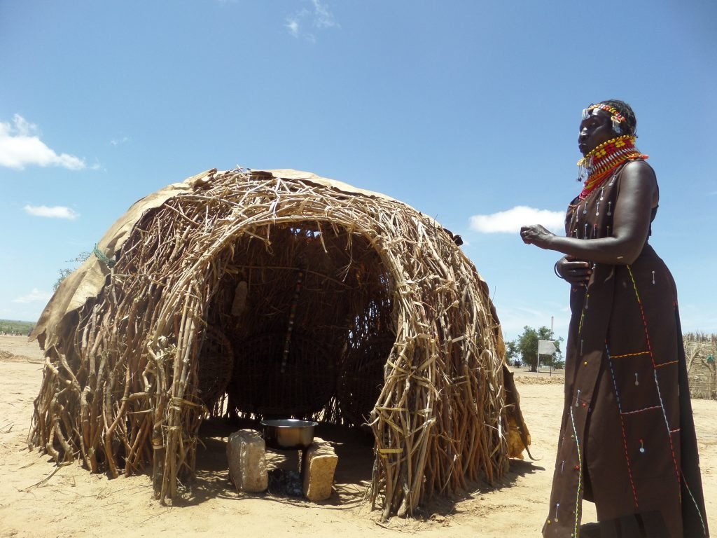 turkana lady standing outsie a traditional kitchen